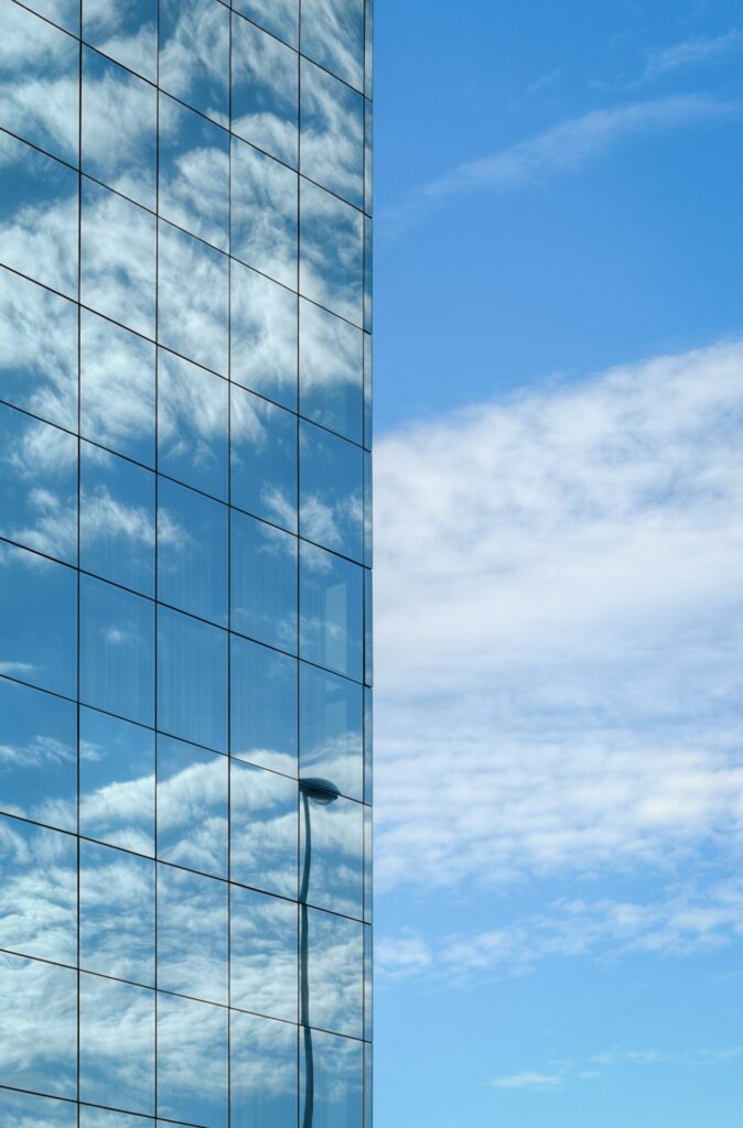 Glass facade reflects the blue sky and white clouds